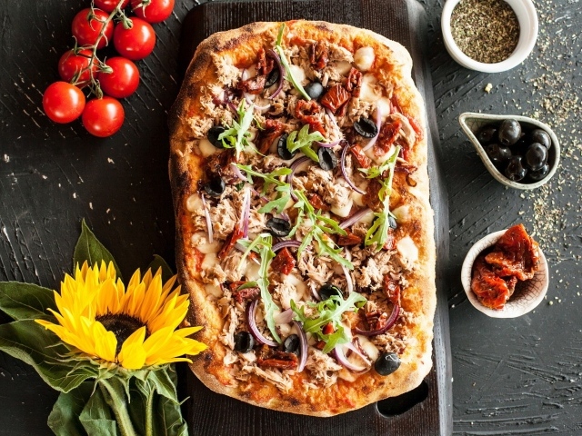 Жареная пицца с мясом на столе с желтым цветком подсолнуха