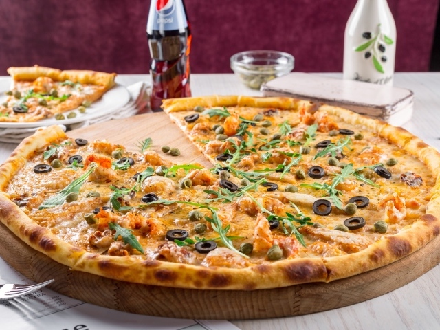 Пицца с оливками на столе с бутылкой пепси