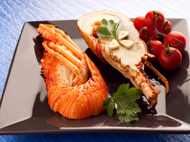 Аппетитный вареный омар на тарелке с помидорами 
