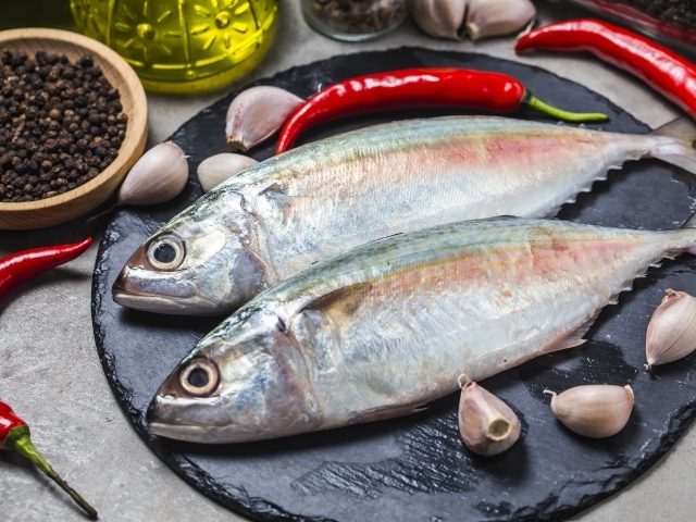 Свежая рыба на столе с красным перцем, чесноком и специями