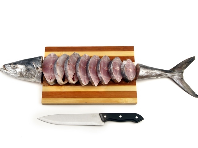 Свежая рыба кусочками на деревянной доске с ножом 