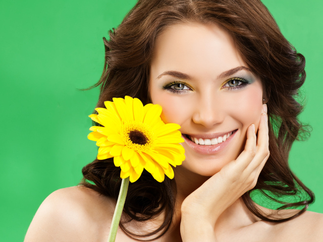 Девушка с красивой улыбкой и цветком желтой герберы в руках
