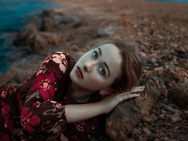 Красивая голубоглазая девушка лежит на камне 