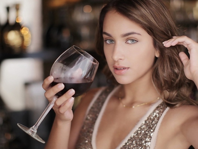 Красивая голубоглазая девушка с бокалом красного вина в руке