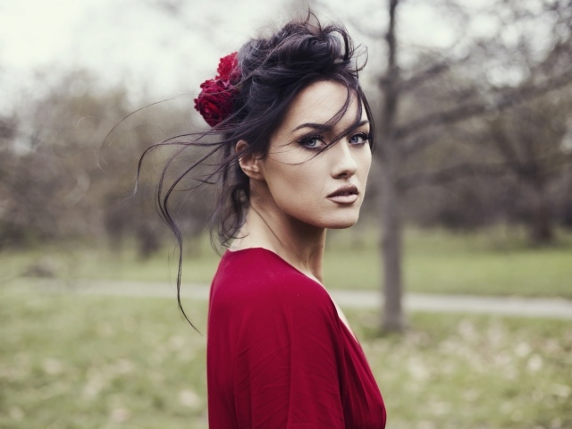 Красивая брюнетка в красном платье с цветком в волосах