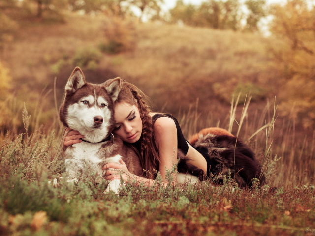 Красивая девушка лежит на траве с собакой породы Хаски