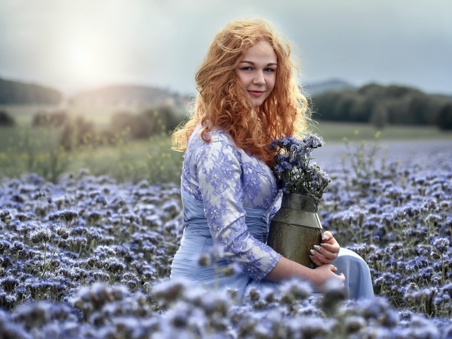 Красивая рыжеволосая девушка собирает цветы