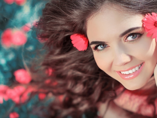 Красивая улыбающаяся девушка с розовыми цветами в волосах 