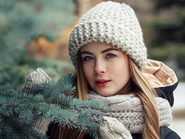 Красивая молодая голубоглазая девушка у еловой ветки зимой