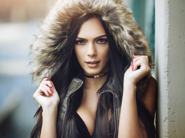 Брюнетка в капюшоне с красными ногтями на руках 