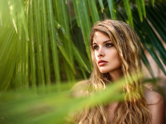 Девушка с волнистыми волосами в пальмовых листьях 