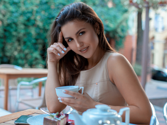 Молодая улыбающаяся девушка с чашкой кофе в кафе