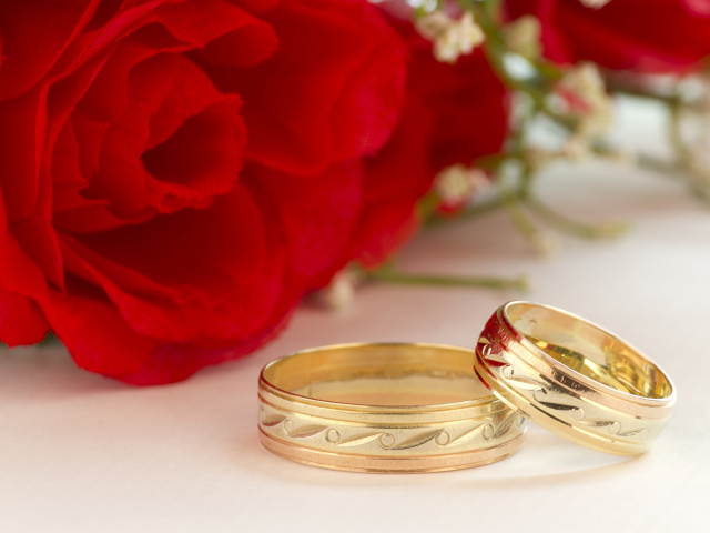 Золотые обручальные кольца с рисунком и красные розы на свадьбу