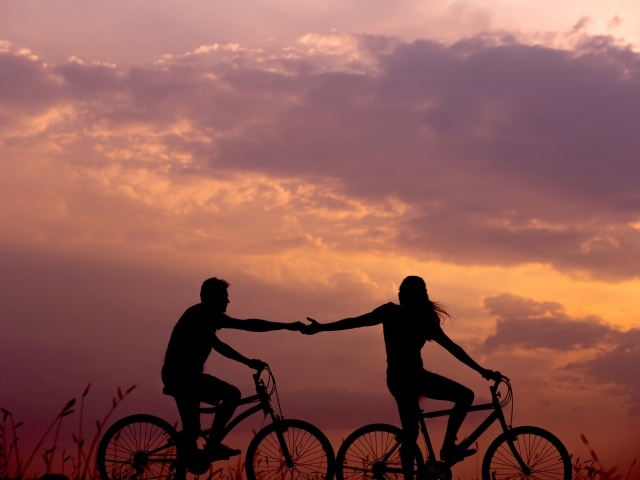Влюбленная пара на велосипедах катается на закате