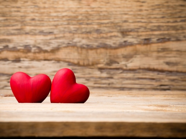 Два красных сердца лежат на деревянной лавке