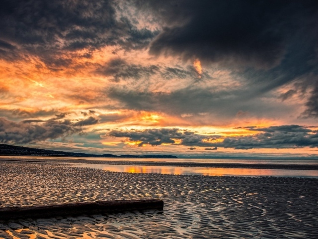 Прохладный закат в хмуром небе  над пляжем
