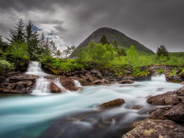 Быстрая вода в горной реке с маленьким водопадом 