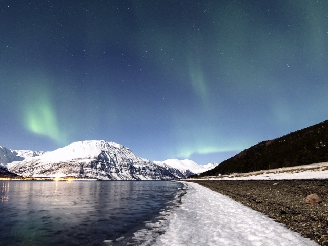 Северное сияние в небе над заснеженными горами 