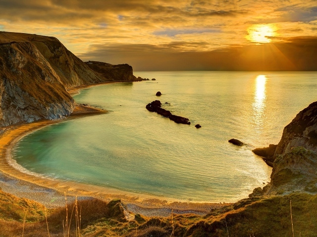 Скалы на берегу океана в лучах солнца на закате