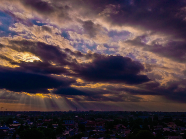 Лучи солнца пробиваются сквозь облака над городом