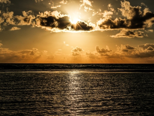 Солнечные лучи пробиваются сквозь облака над океаном