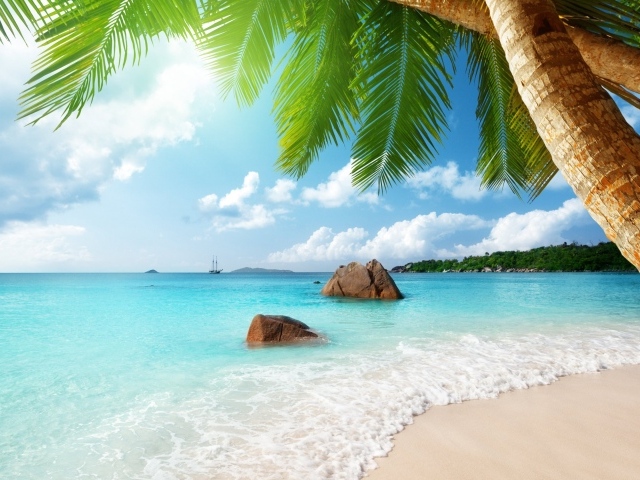 Голубая вода океана омывает белый песок на тропическом пляже