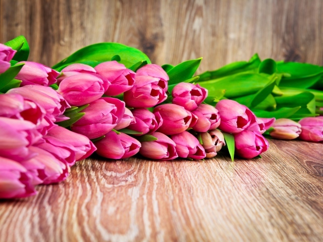 Букет розовых тюльпанов лежит на деревянной поверхности