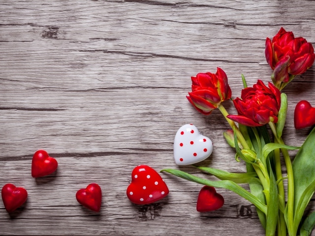 Красные красивые тюльпаны с сердечками на деревянной поверхности