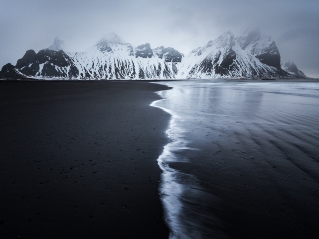 Заснеженные горы у пустынного пляжа