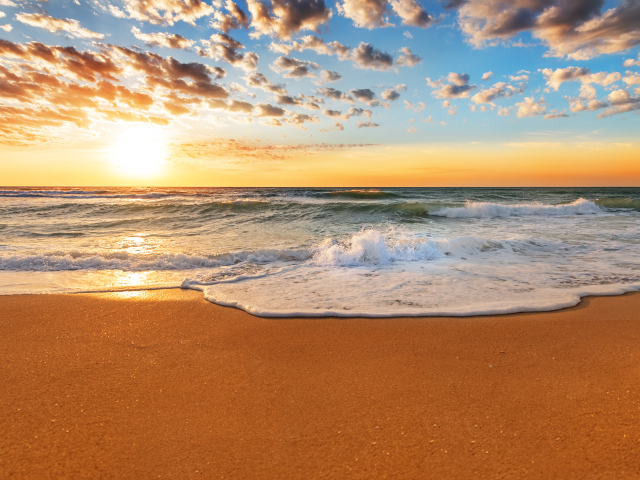 Волна омывает горячий желтый песок на берегу моря