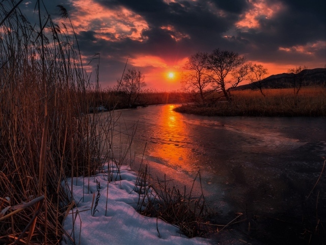 Закат солнца над покрытой льдом рекой