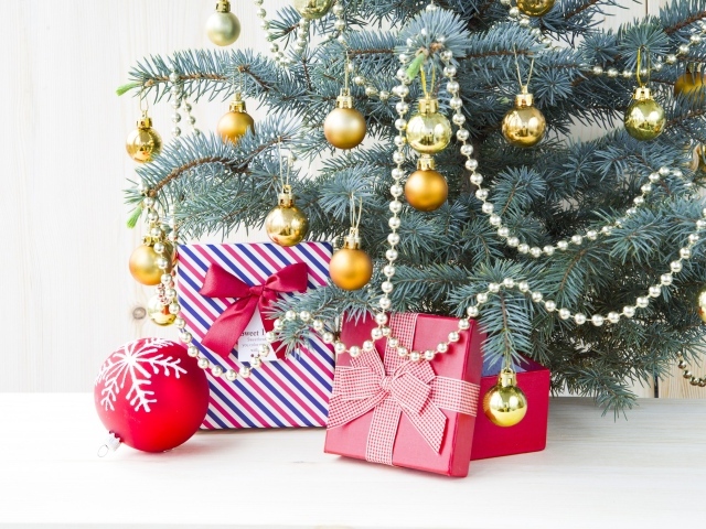 Подарки под зеленой наряженной елкой с золотыми шарами