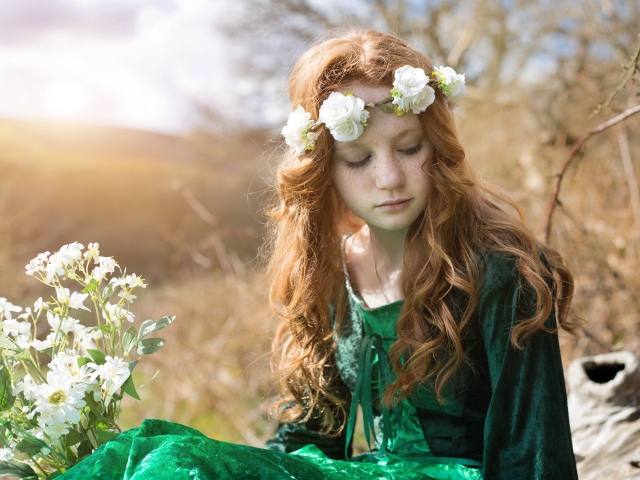 Милая рыжеволосая девочка в зеленом платье с венком на голове