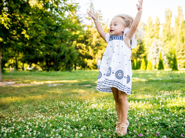 Девочка в красивом платье гуляет на зеленом лугу