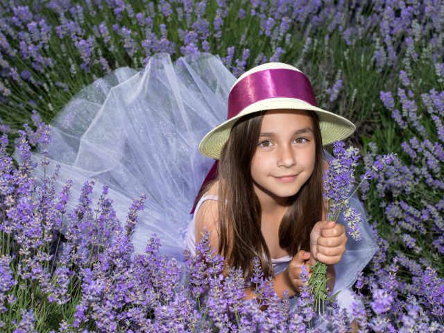 Девочка в шляпе лежит в фиолетовых цветах лаванды