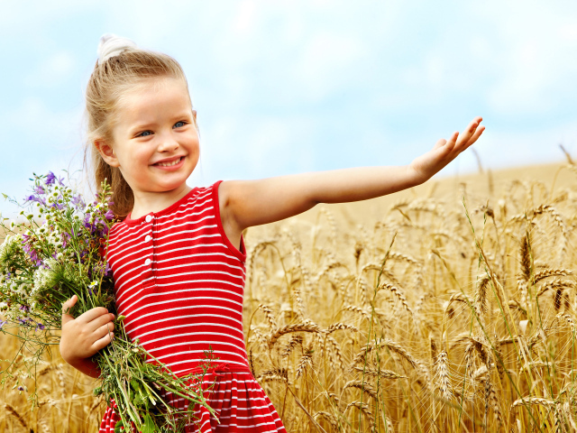 Маленькая девочка с букетом полевых цветов гуляет по полю пшеницы