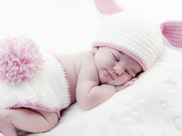Маленький спящий ребенок в вязаном костюме зайчика