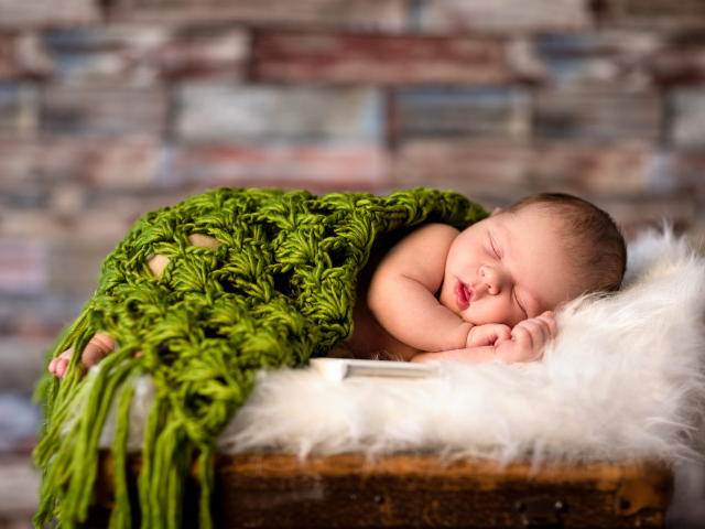 Спящий младенец под зеленым вязаным пледом
