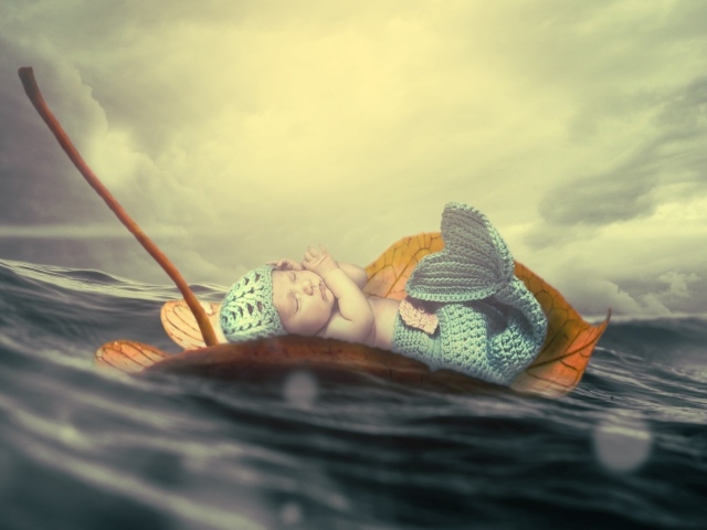 Маленький грудной ребенок в костюме русалки плывет на листе в океане