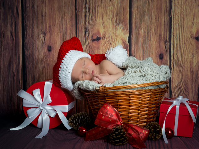 Маленький грудной ребенок спит в плетеной корзине с новогодними подарками