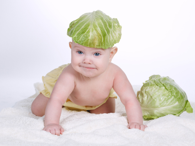 Маленький грудной ребенок с капустным листом на голове