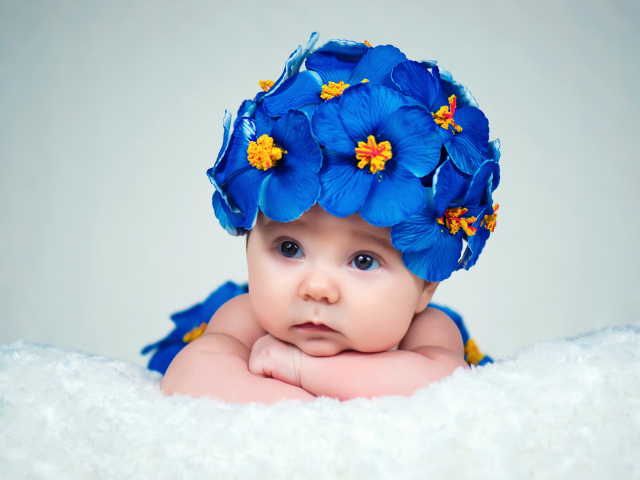 Маленький ребенок в красивой шапке с голубыми цветами