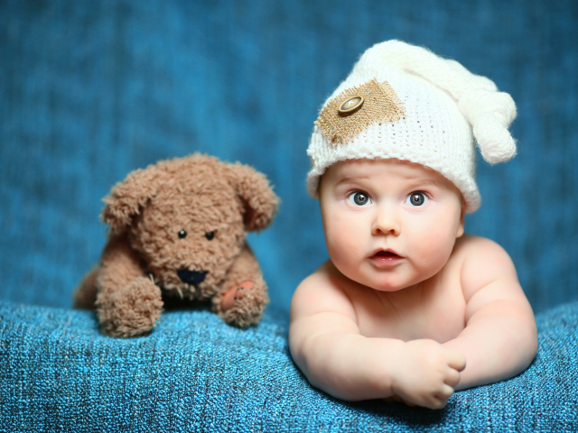 Маленький ребенок с красивой белой шапке с плюшевым медведем