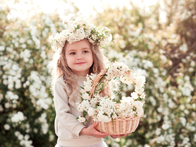 Милая маленькая девочка с венком на голове и корзиной белых цветов