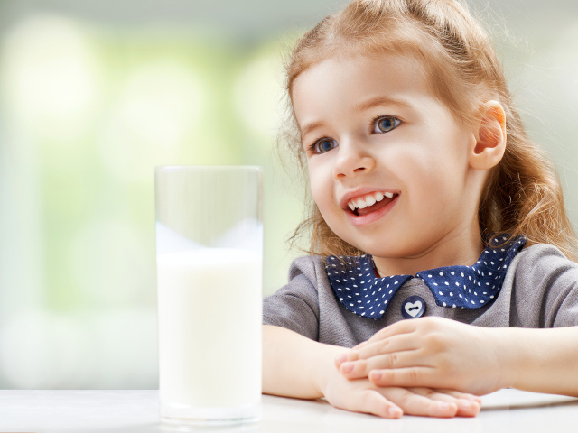 Красивая кареглазая девочка со стаканом молока