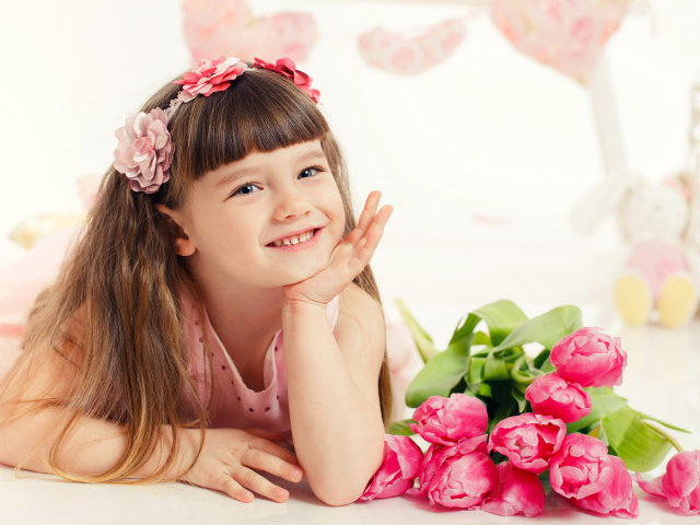 Красивая длинноволосая улыбающаяся девочка с букетом розовых тюльпанов