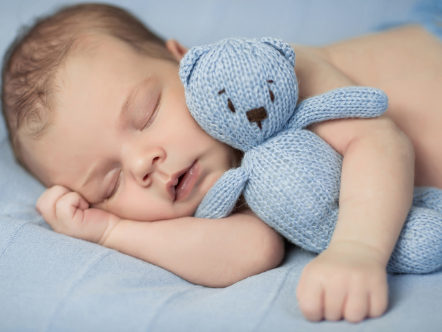 Милый спящий младенец с вязаной мягкой игрушкой