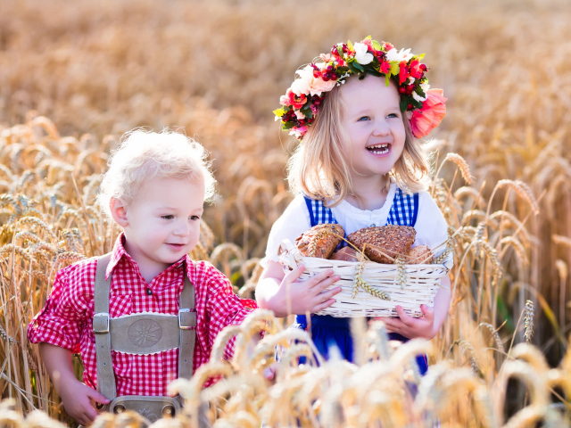 Маленькие мальчик и девочка на поле пшеницы с корзиной свежей выпечки