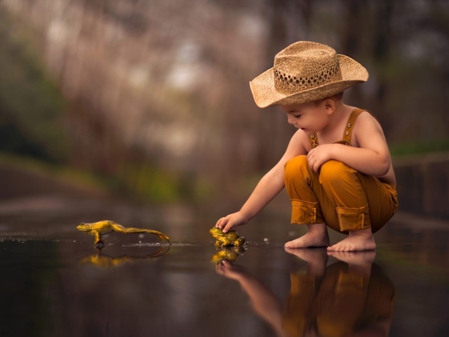 Маленький мальчик играет с лягушками 