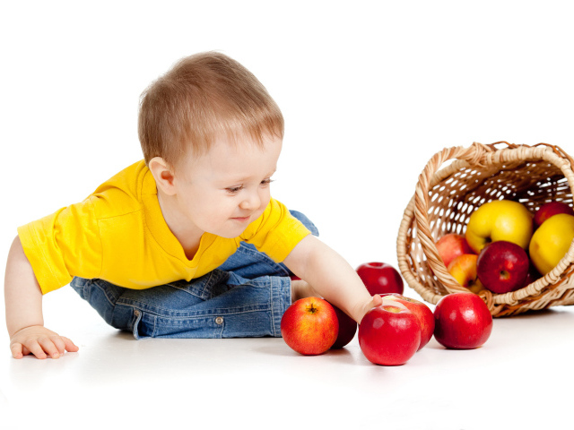 Маленький мальчик с корзиной спелых яблок на белом фоне